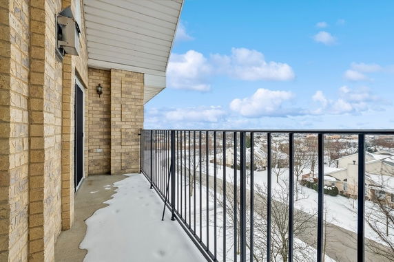 View from a balcony with snow-covered surroundings and clear blue sky.