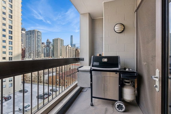 Balcony view with a grill and city skyline in the background.
