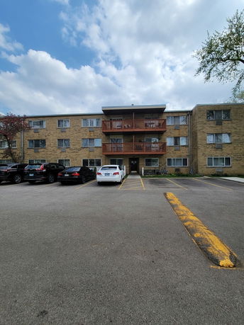 Front view of a multi-story apartment building with a parking area.