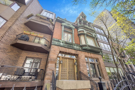Front view of an ornate residential building with balconies and decorative stonework.