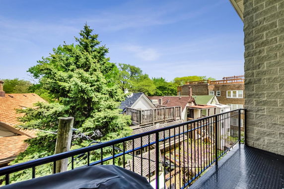 View from a balcony overlooking trees and neighboring houses.