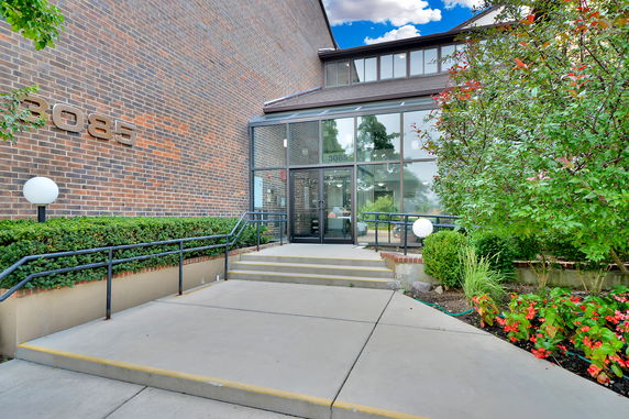 Front view of a brick building with a glass entrance and external steps.