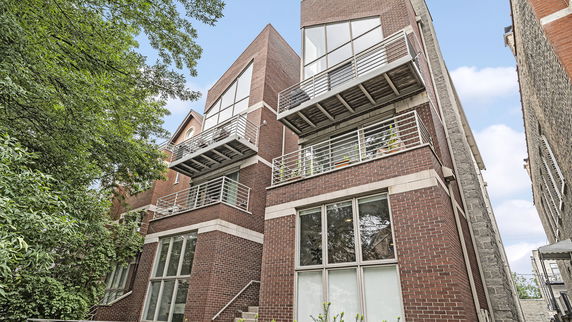 Front view of a multi-story brick building with modern design and balconies.