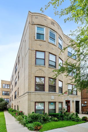 Front view of a multi-story brick apartment building with multiple windows.