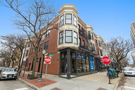 Front view of a multi-story brick building with large windows and a corner entrance.