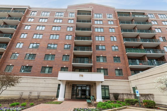 Front view of a multi-story brick apartment building with balconies.