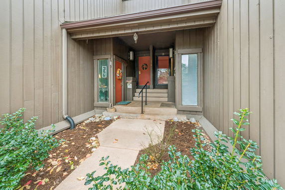 Front view of a house entrance with wooden siding and two doors leading to different units.