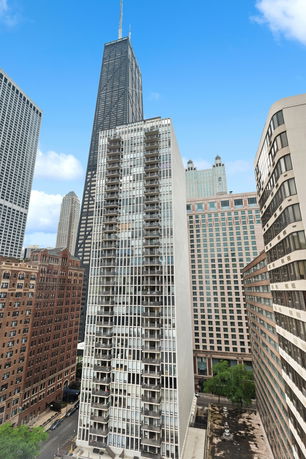 Front view of a tall residential building with multiple balconies in an urban setting.