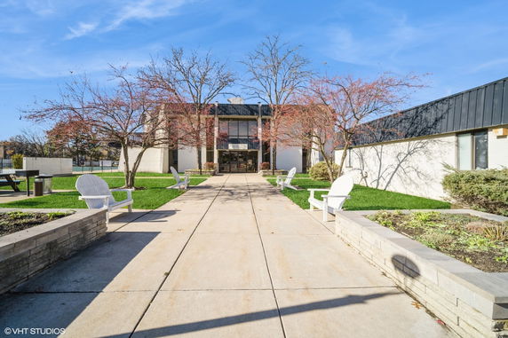 Front view of a modern building with glass entrance and surrounding green areas.