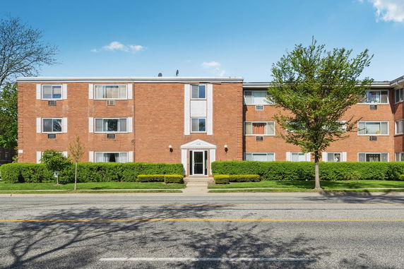 Front view of a brick apartment building with multiple windows and a central entrance.