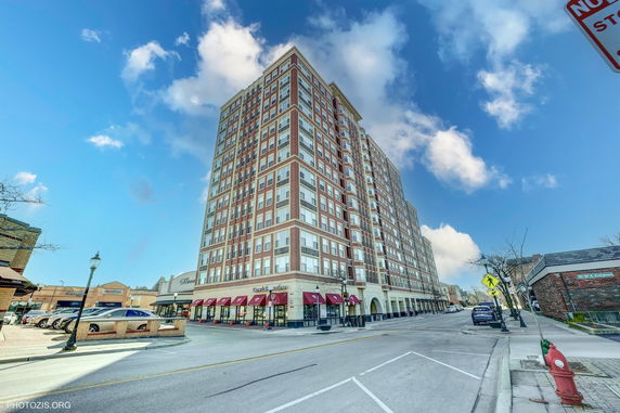Front view of a multi-story building with red brick facade and large windows.