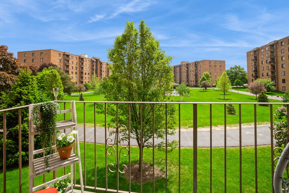 View of multiple apartment buildings and landscaped green area from a balcony.
