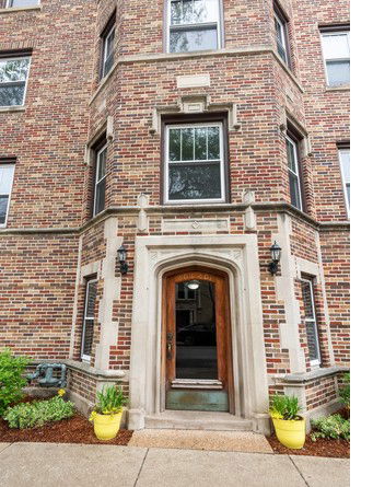 Front view of a multi-story brick building with a detailed arch entrance.