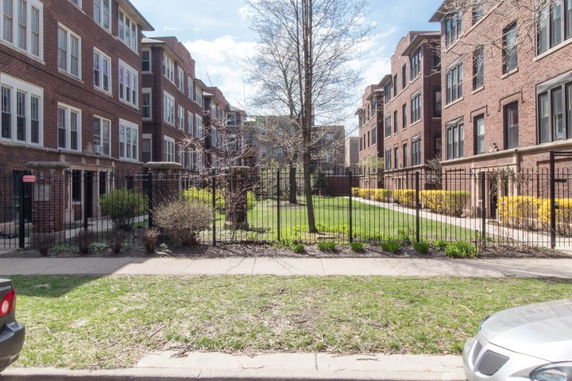 Front view of multiple-story brick buildings with fenced front yards.