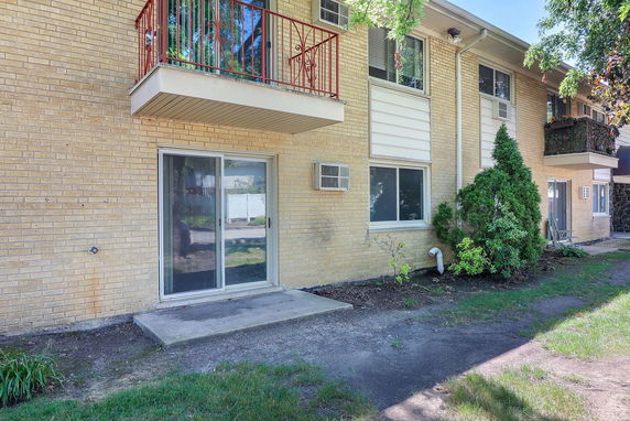 Front view of a two-story brick building with balconies and sliding glass doors.