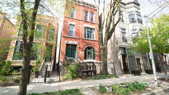Front view of a multi-story brick townhouse with arched windows and a gated entrance.