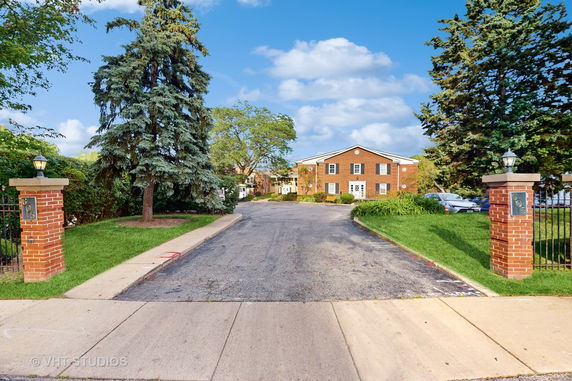 Front view of a two-story brick building with a driveway and landscaped entrance.