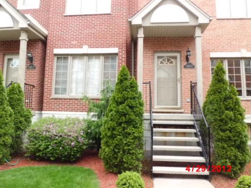 Front view of a townhouse with a small staircase and red brick exterior.