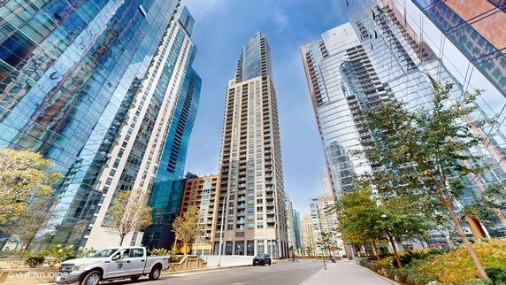 Front view of a tall, modern high-rise building with glass facade surrounded by other skyscrapers.