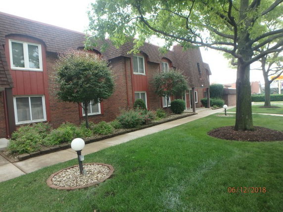 Front view of a two-story brick apartment building with manicured landscaping.