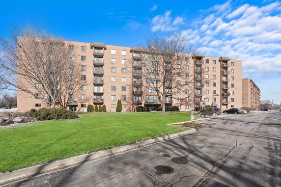 Front view of a multi-story apartment building with balconies and brick exterior.