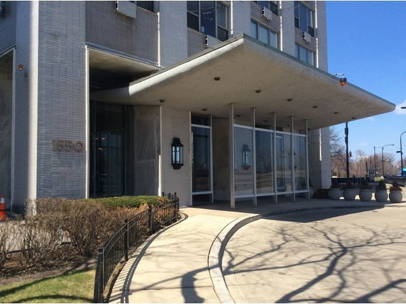 Front view of a multi-story building with a glass entrance and covered walkway.