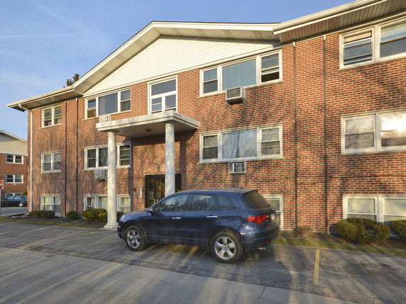 Front view of a two-story brick apartment building with a car parked in front.