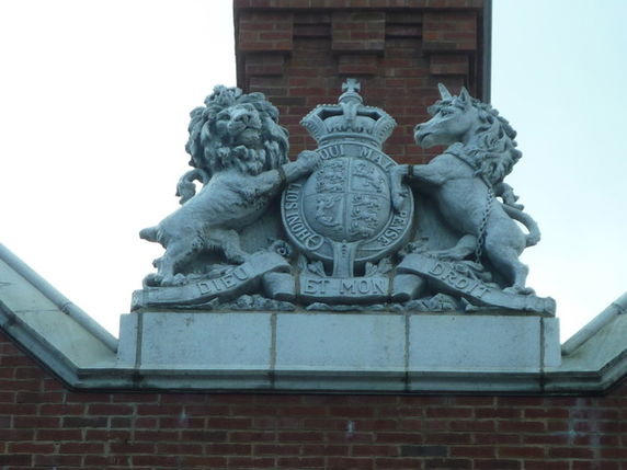 Detailed architectural feature with a lion and unicorn crest on a brick building.