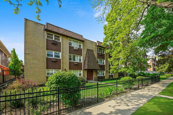 Front view of a three-story residential building with a brick facade and brown accents.