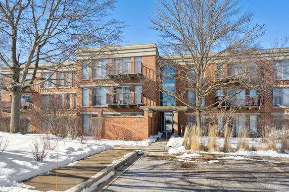 Front view of a multi-story brick apartment building with balconies.