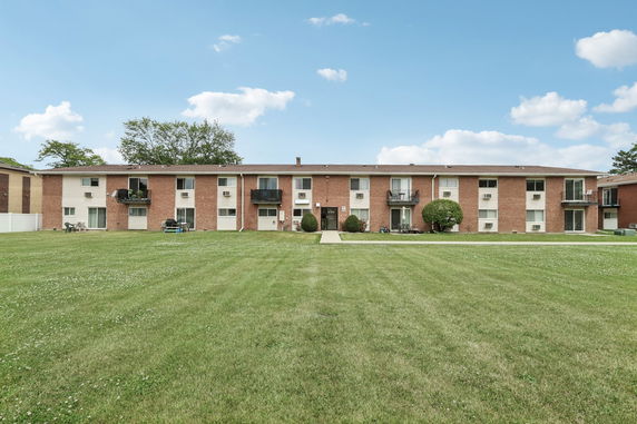 Front view of a multi-story brick apartment building with balconies.