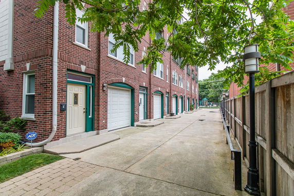 Row of brick townhouses with garages along a driveway.