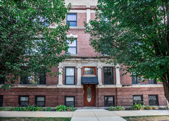 Front view of a multi-story brick building with decorative columns at the entrance.