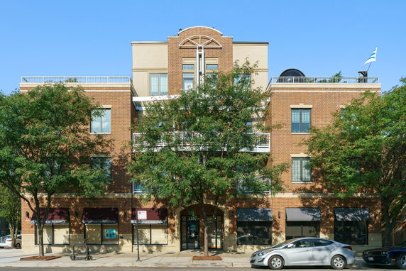Front view of a multi-story brick building with large windows and a symmetrical design.