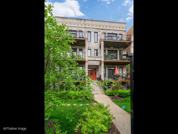 Front view of a three-story residential building with balconies.