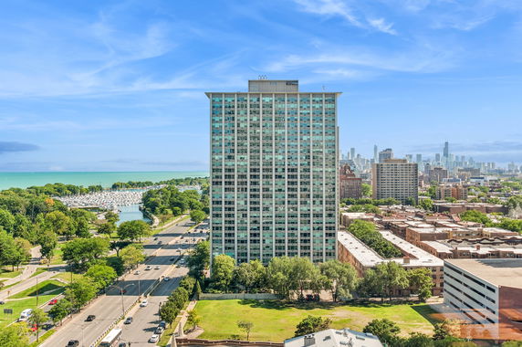View of a tall residential building with cityscape and waterfront in the background.
