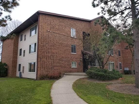 Front view of a multi-story brick building with a pathway leading to the entrance.