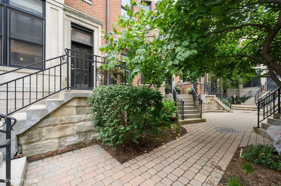 Front view of a brick townhouse with a staircase leading to a black door.