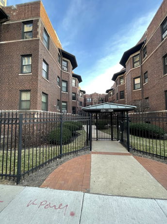 Front view of a brick apartment building with gated entrance.