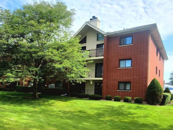 Front view of a three-story brick apartment building with balconies.