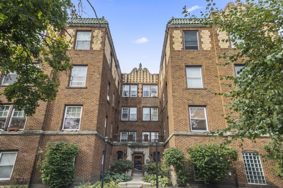 Front view of a multi-story brick apartment building with decorative elements.