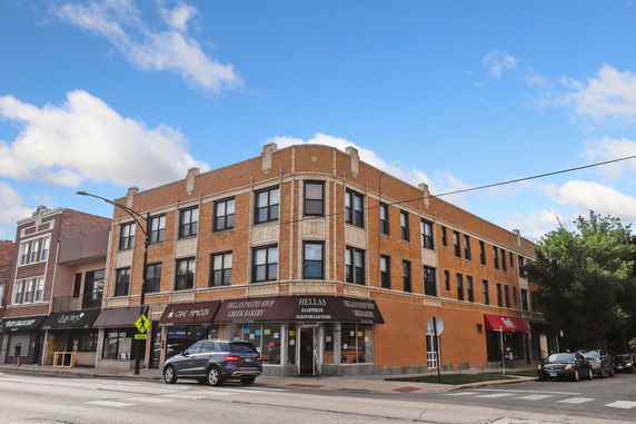 Front view of a three-story brick building with commercial spaces on the ground floor.