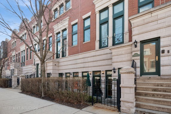 Front view of a row of brick townhouses with stairs leading to each entrance.