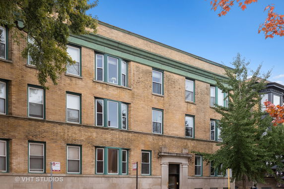 Front view of a three-story brick building with decorative trim around windows.