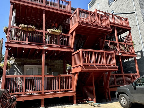 Rear view of a multi-story building with multiple wooden balconies and a staircase.
