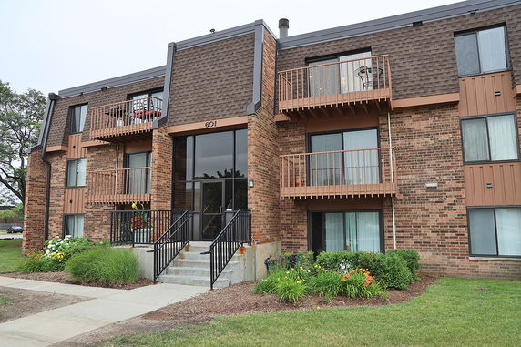 Front view of a multi-story brick apartment building with balconies.