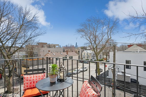 View from a balcony overlooking a neighborhood with buildings and trees in the distance.