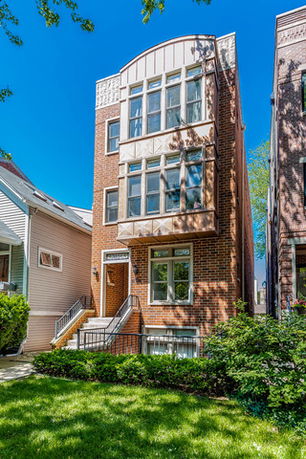 Front view of a multi-story brick house with large windows.