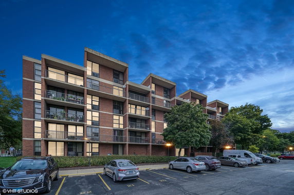 Front view of a multi-story brick apartment building with balconies.