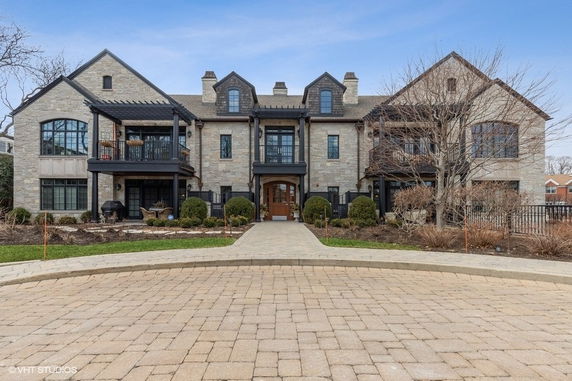 Front view of a large multi-story house with stone exterior and multiple balconies.